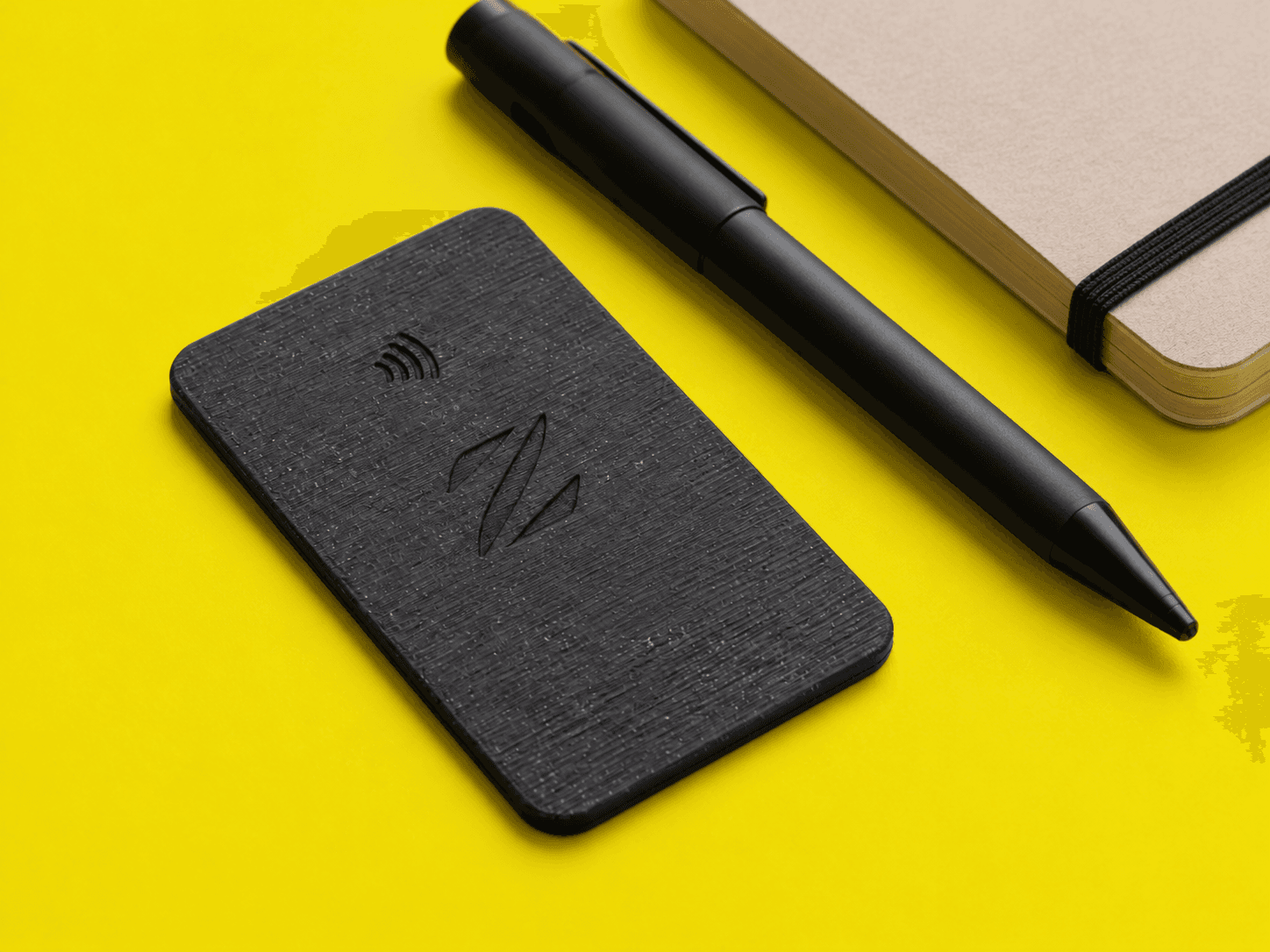 Tarjeta NFC negra junto a un cuaderno y un bolígrafo